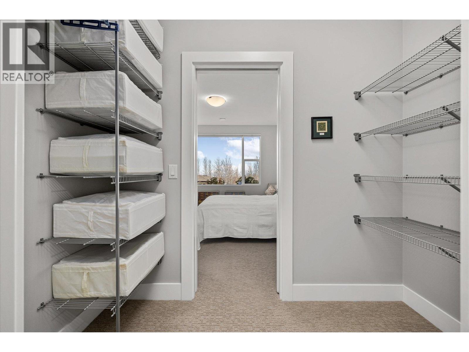 Walk-through closet leading to a cheater ensuite - 468 Sparrow Hawk Court, Kelowna, BC - Indoor With Storage