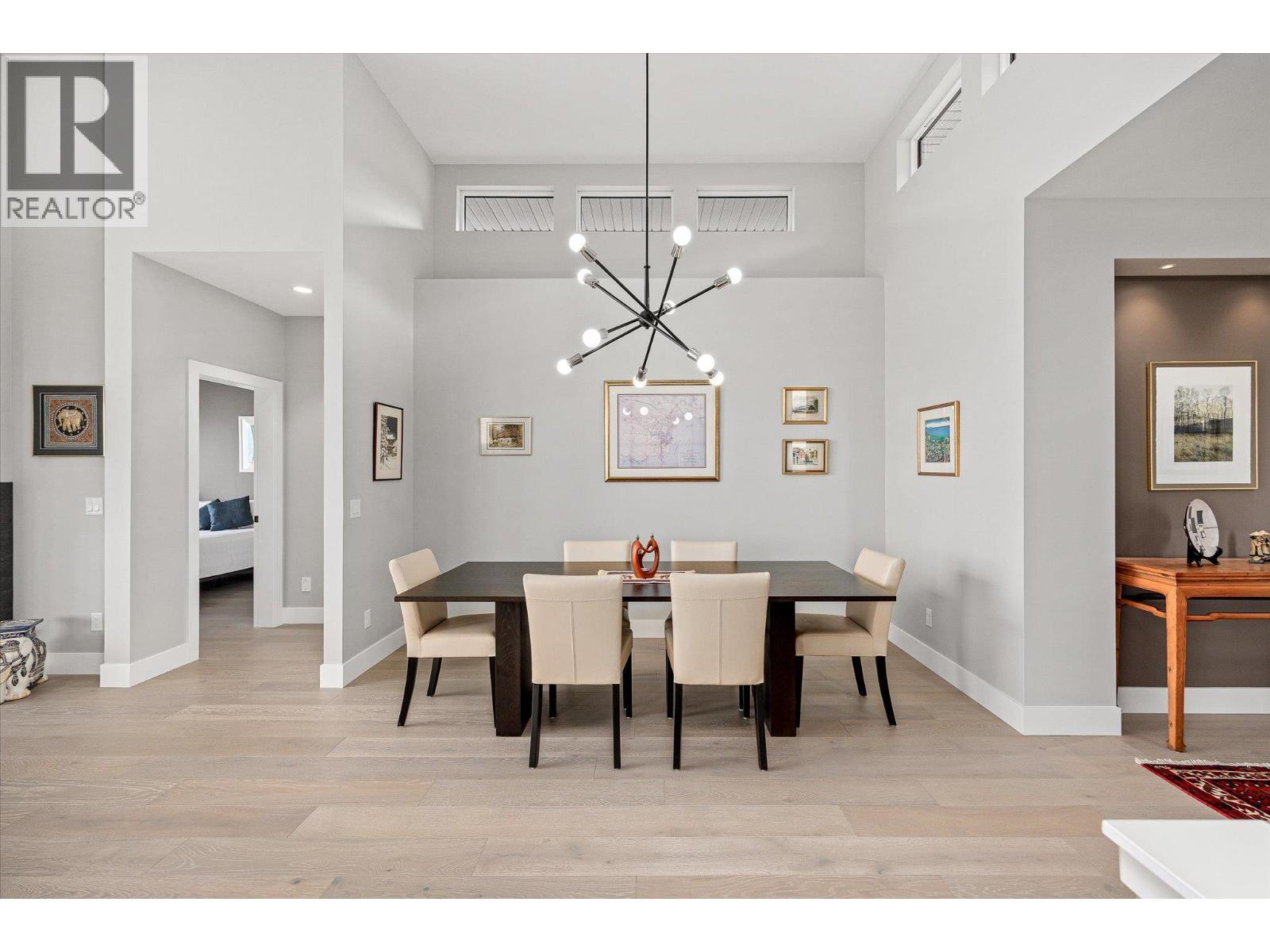 Seating for up to 8, soaring 13ft+ ceilings and a designer overhead light fixture - 468 Sparrow Hawk Court, Kelowna, BC - Indoor Photo Showing Dining Room