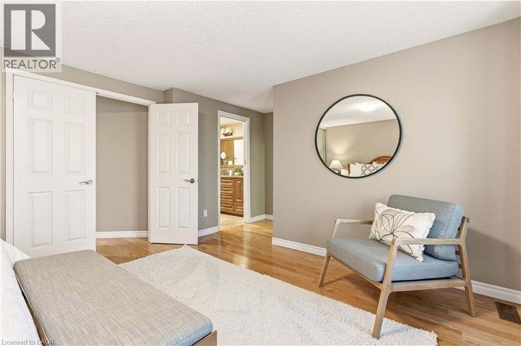 Bedroom with ensuite bath, light wood-style flooring, and a textured ceiling - 1489 Litchfield Road, Oakville, ON - Indoor