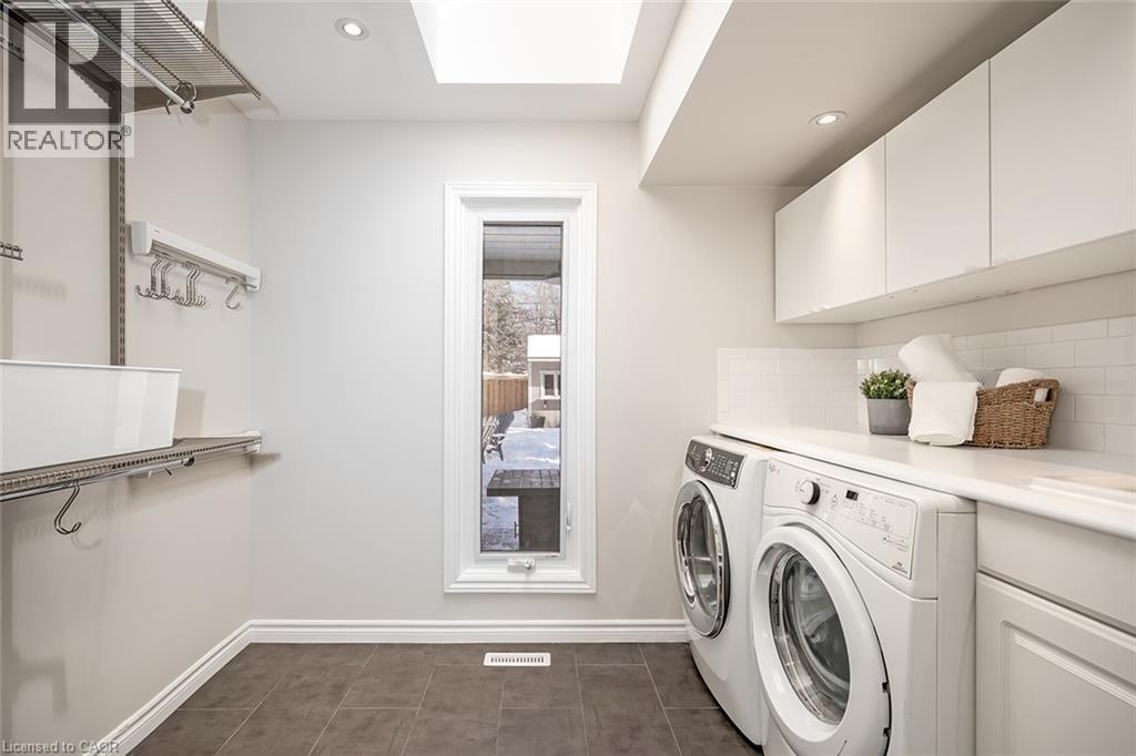 Laundry area with a skylight, recessed lighting, washing machine and dryer, and cabinet space - 4226 Dunvegan Road, Burlington, ON - Indoor Photo Showing Laundry Room
