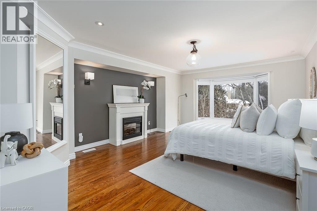 Bedroom featuring a glass covered fireplace, crown molding, and wood finished floors - 4226 Dunvegan Road, Burlington, ON - Indoor Photo Showing Bedroom With Fireplace