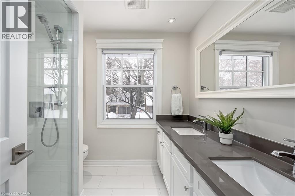 Bathroom featuring double vanity, a shower stall, and light tile patterned floors - 4226 Dunvegan Road, Burlington, ON - Indoor Photo Showing Bathroom