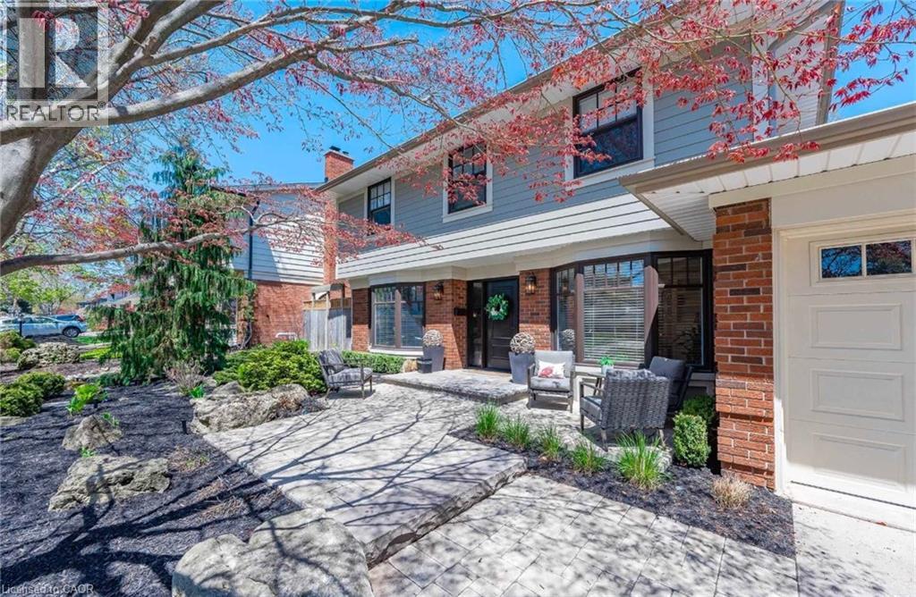 View of front of home with brick siding, a patio area, a chimney, and an outdoor living space - 4226 Dunvegan Road, Burlington, ON - Outdoor With Deck Patio Veranda