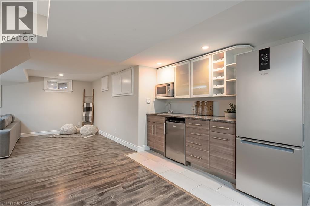 Bar area with appliances with stainless steel finishes, open shelves, light wood-style flooring, recessed lighting, and brown cabinetry - 4226 Dunvegan Road, Burlington, ON - Indoor