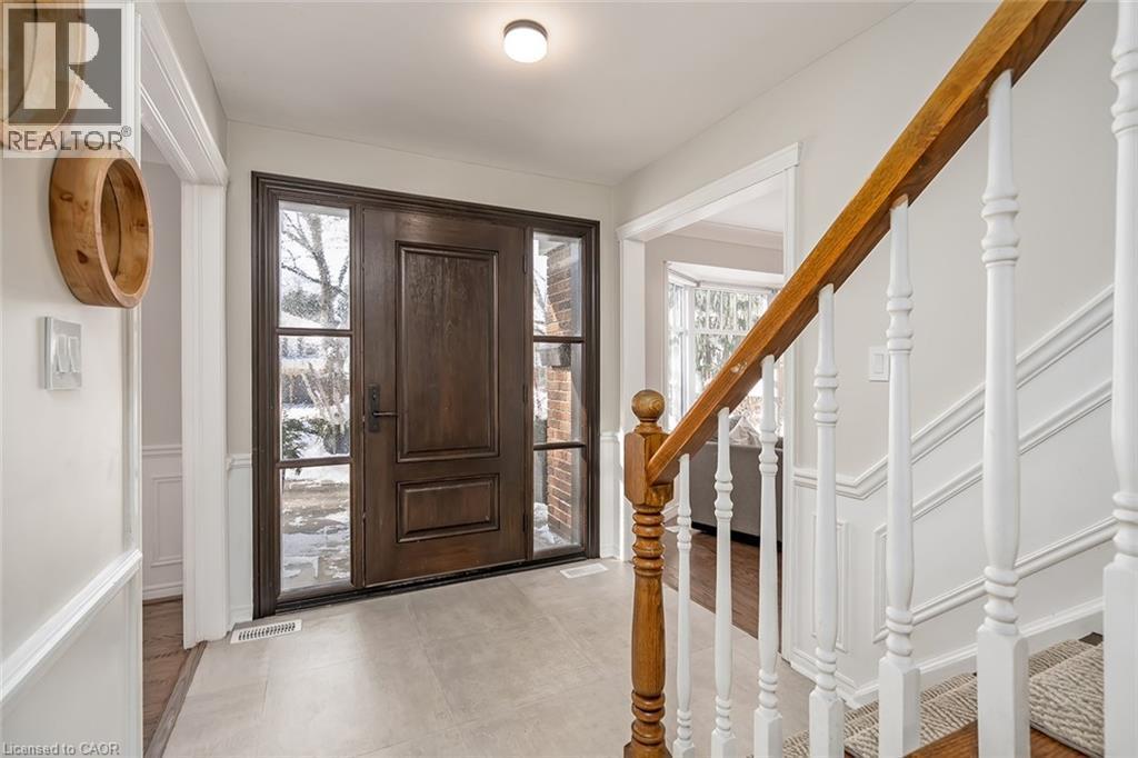 Entryway featuring stairs, wainscoting, a decorative wall, and light tile patterned floors - 4226 Dunvegan Road, Burlington, ON - Indoor Photo Showing Other Room
