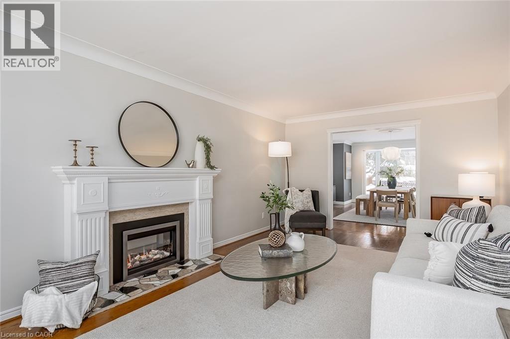 Living area featuring wood finished floors, ornamental molding, and a fireplace with flush hearth - 4226 Dunvegan Road, Burlington, ON - Indoor Photo Showing Living Room With Fireplace