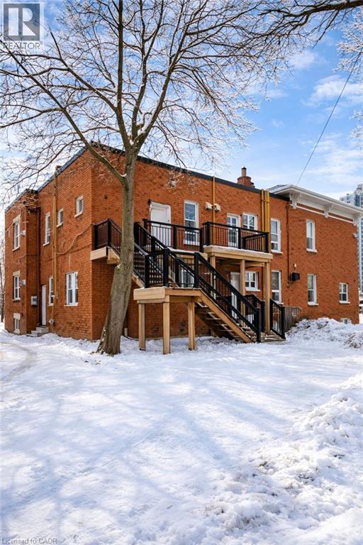 Snow covered rear of property featuring stairs, a deck, brick siding, and a chimney - 46 College Street, Kitchener, ON - Outdoor