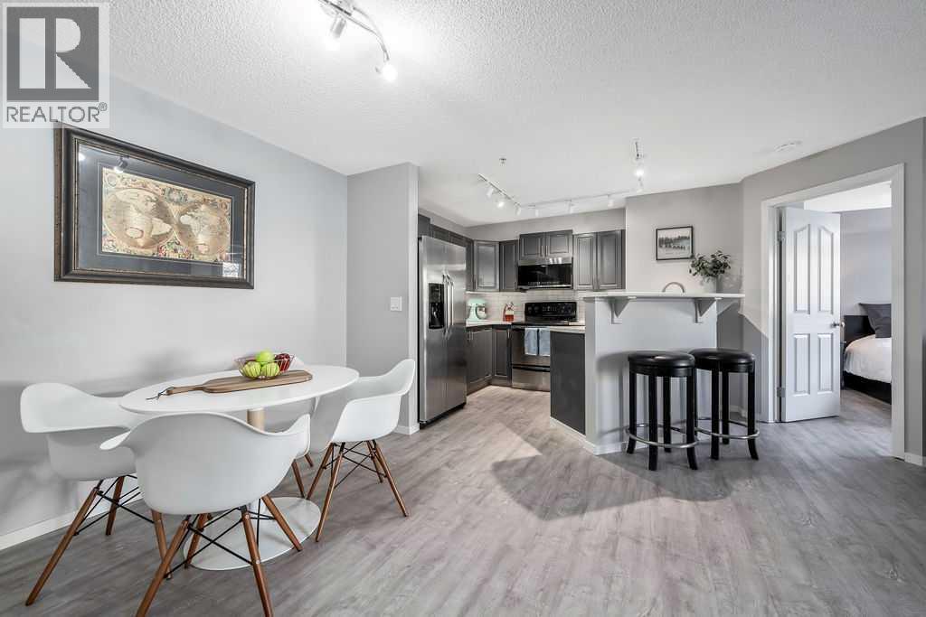 Dining Area and Kitchen with Breakfast Bar - 1120, 4975 130 Avenue Se, Calgary, AB - Indoor Photo Showing Dining Room
