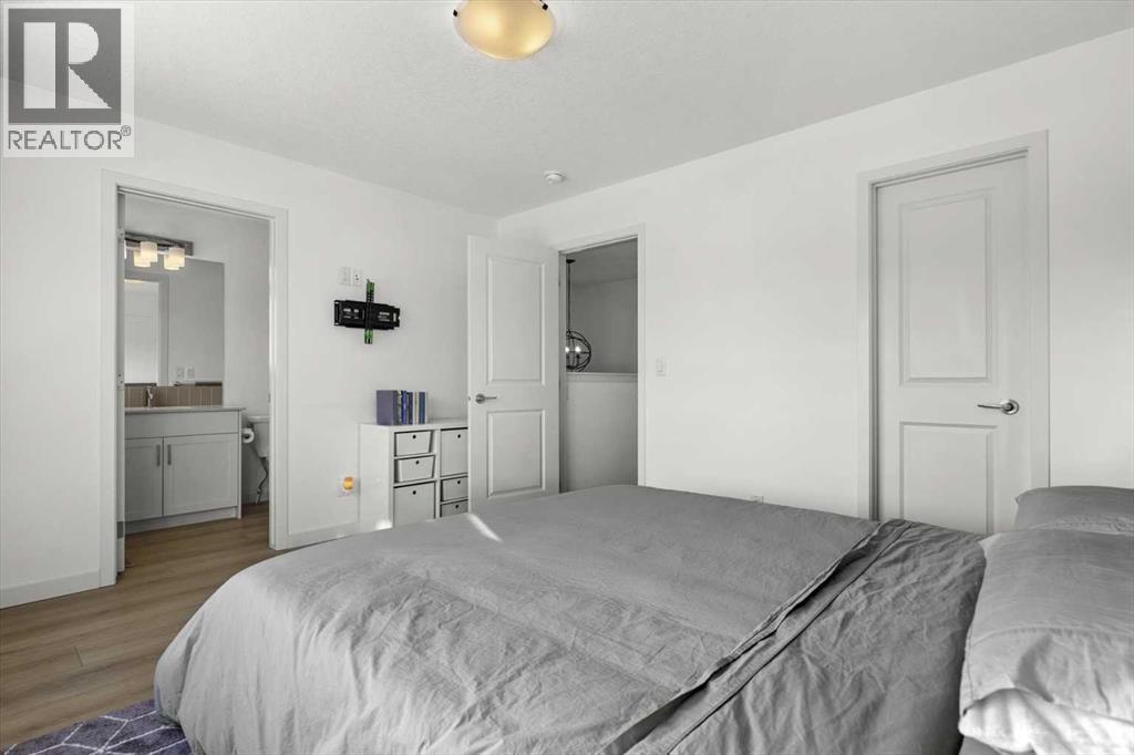 The spacious primary suite offers a relaxing retreat with seamless access to a walk-in closet and private ensuite - 59 Wolf Hollow Way Se, Calgary, AB - Indoor Photo Showing Bedroom