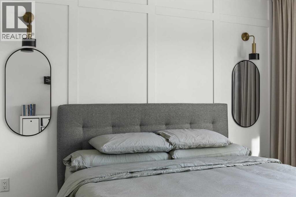 The primary suite is anchored by a striking feature wall with ambient lighting, creating a warm and inviting space - 59 Wolf Hollow Way Se, Calgary, AB - Indoor Photo Showing Bedroom