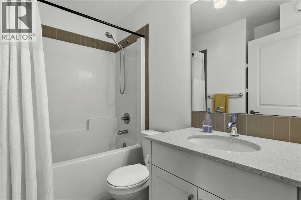 The shared upper-level bathroom features a clean, functional design with neutral finishes and a full tub-shower combination - 59 Wolf Hollow Way Se, Calgary, AB - Indoor Photo Showing Bathroom