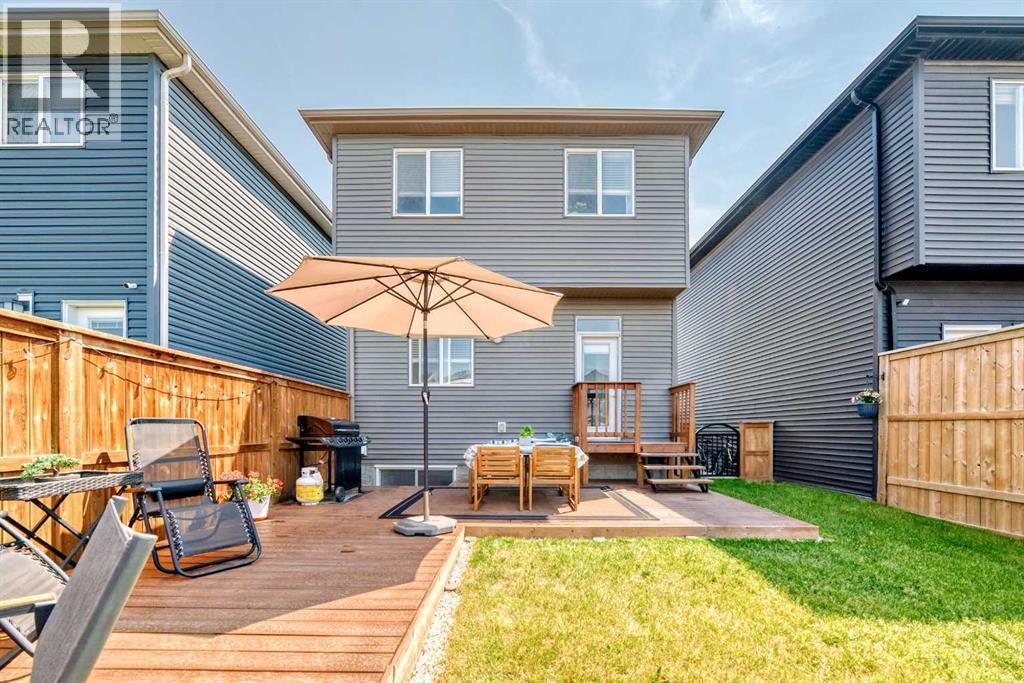 In warmer months, the backyard transforms into an inviting outdoor living area with a spacious deck and green space - 59 Wolf Hollow Way Se, Calgary, AB - Outdoor With Deck Patio Veranda With Exterior