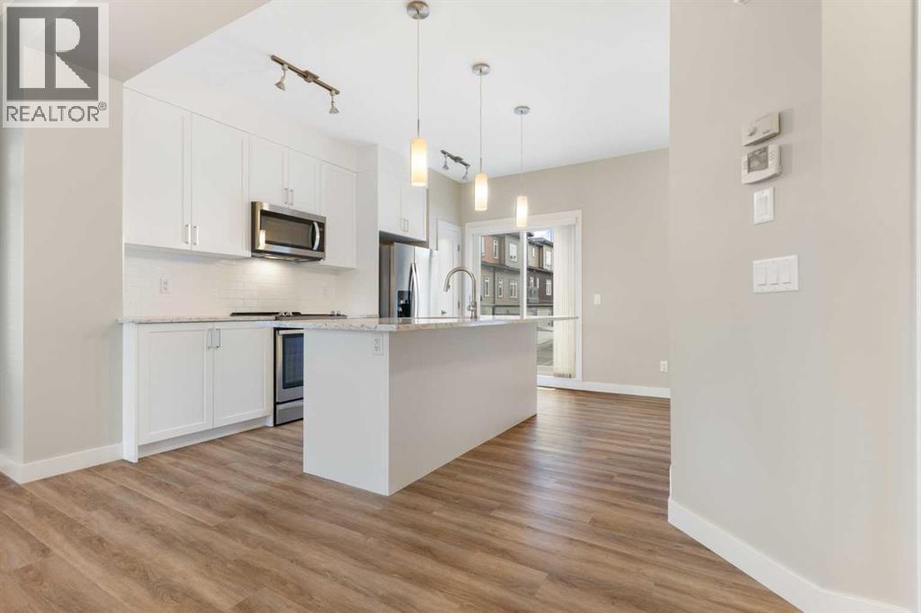 Kitchen, quartz counters, tall upper cabinets, large island with breakfast bar, pendant and track lighting - 217 Sage Bluff Drive Nw, Calgary, AB - Indoor Photo Showing Kitchen With Upgraded Kitchen