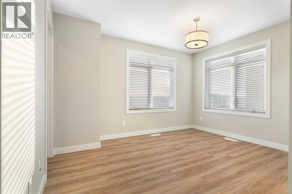 Front primary bedroom, vinyl plank flooring, 2 large windows - 217 Sage Bluff Drive Nw, Calgary, AB - Indoor Photo Showing Other Room