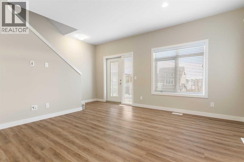 Living room, stairs to upper level, door to balcony - 217 Sage Bluff Drive Nw, Calgary, AB - Indoor Photo Showing Other Room