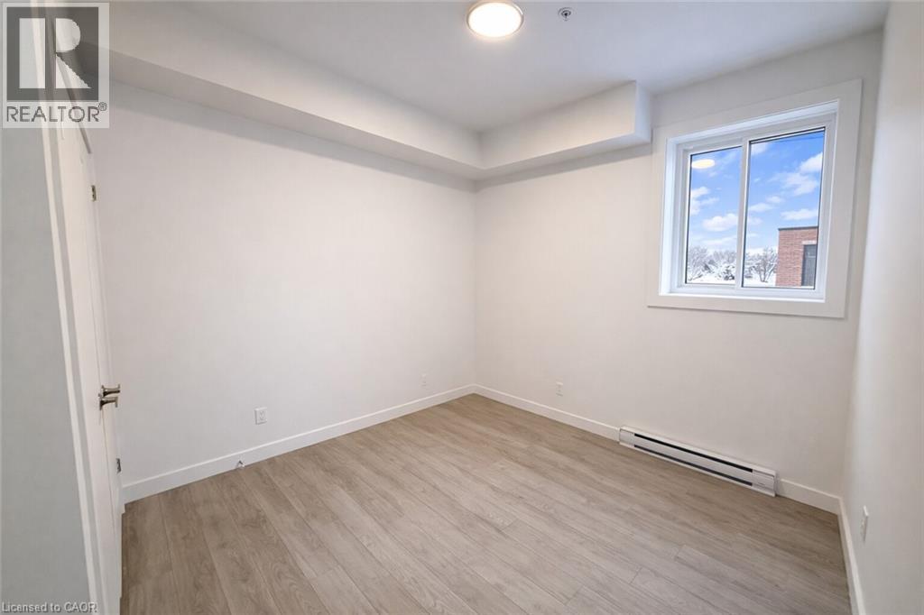 Unfurnished room with a baseboard heating unit, light wood-style flooring, and fire sprinkler in ceiling - 228 Margaret Avenue, Kitchener, ON - Indoor Photo Showing Other Room