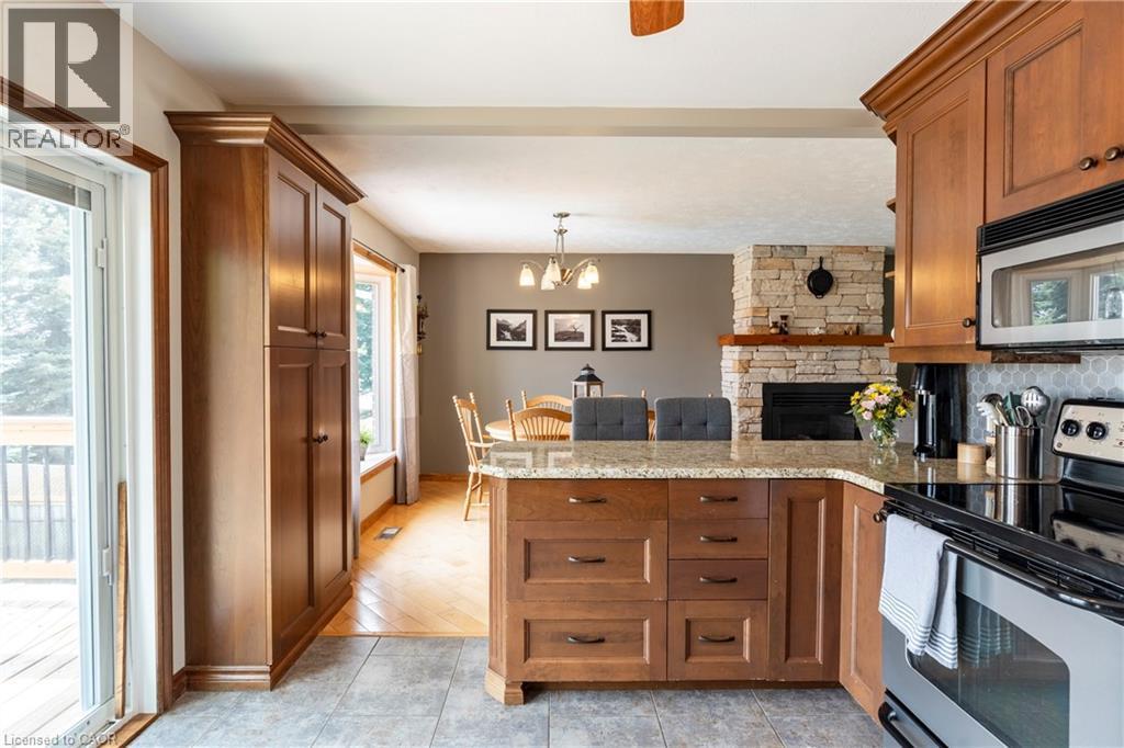 Kitchen featuring stainless steel appliances, brown cabinetry, hanging light fixtures, a chandelier, and light stone countertops - 29 Armstrong Crescent, Grey Highlands, ON - Indoor Photo Showing Kitchen