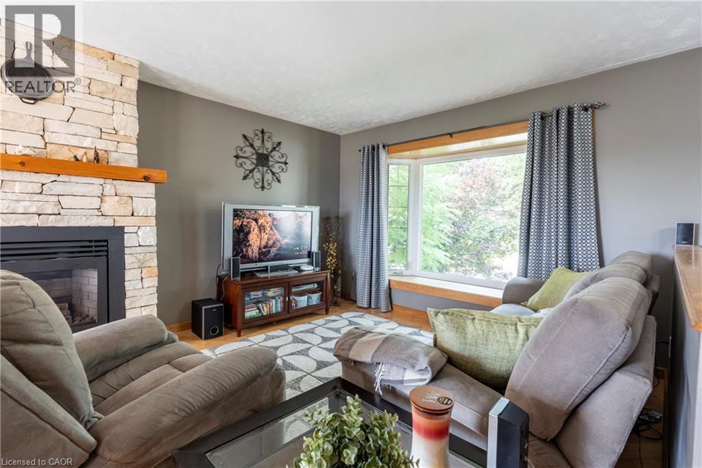 Living room featuring a stone fireplace and wood finished floors - 29 Armstrong Crescent, Grey Highlands, ON - Indoor Photo Showing Living Room With Fireplace
