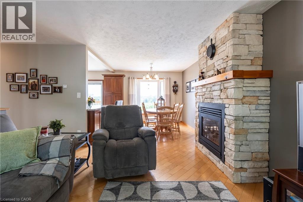 Living area with light wood-type flooring, a fireplace, a textured ceiling, and a chandelier - 29 Armstrong Crescent, Grey Highlands, ON - Indoor Photo Showing Living Room With Fireplace