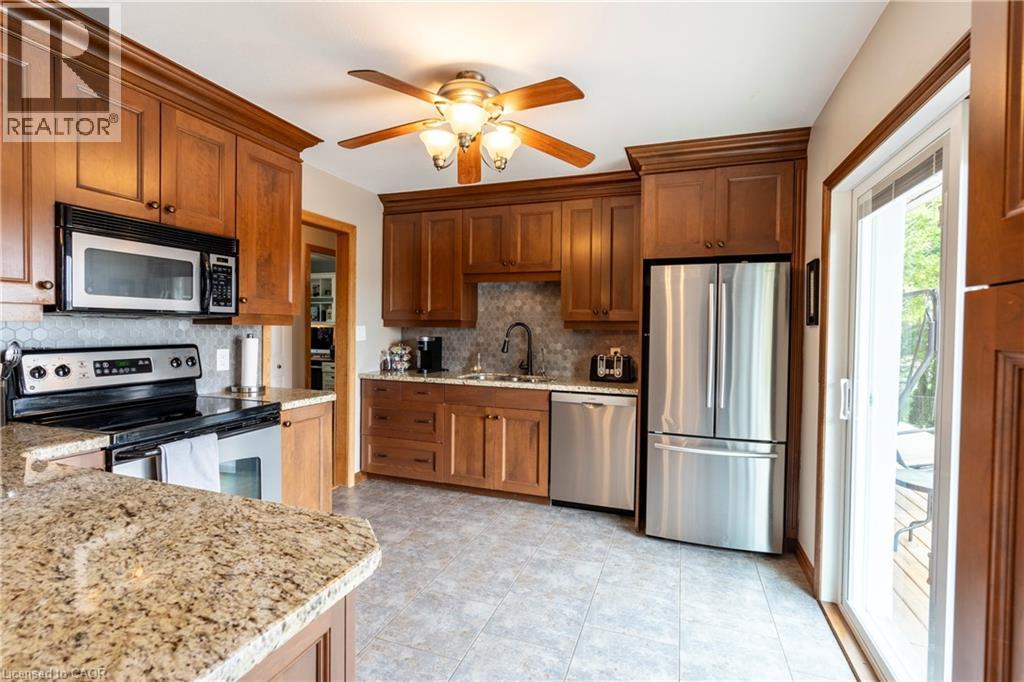 Kitchen featuring appliances with stainless steel finishes, light stone countertops, ceiling fan, and brown cabinets - 29 Armstrong Crescent, Grey Highlands, ON - Indoor Photo Showing Kitchen