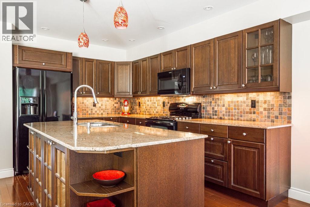 Kitchen with black appliances, a sink, open shelves, dark wood-type flooring, and light stone counters - 330 Strathcona Drive, Burlington, ON - Indoor Photo Showing Kitchen