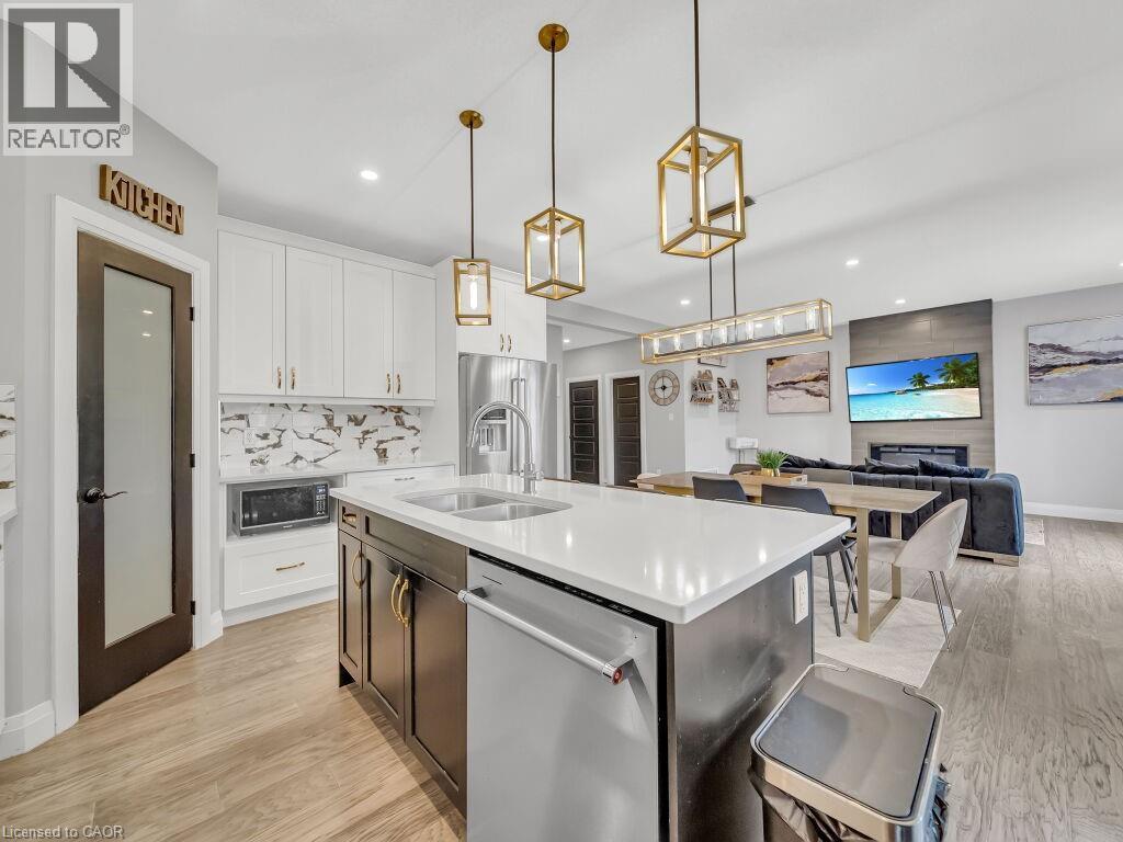 Kitchen featuring white cabinetry, light wood-type flooring, stainless steel appliances, an island with sink, and recessed lighting - 3374 Oriole Drive, London, ON - Indoor Photo Showing Kitchen With Double Sink With Upgraded Kitchen