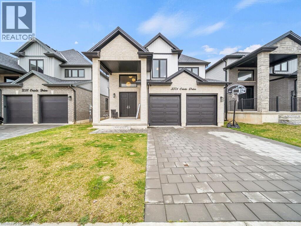 View of front facade with a front yard, driveway, a garage, and brick siding - 3374 Oriole Drive, London, ON - Outdoor With Facade