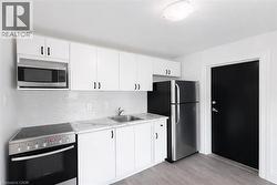 Kitchen with stainless steel appliances, white cabinetry, and decorative backsplash -