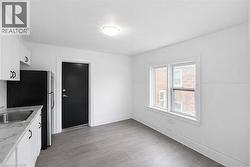 Kitchen with white cabinetry, freestanding refrigerator, and light wood-style floors -