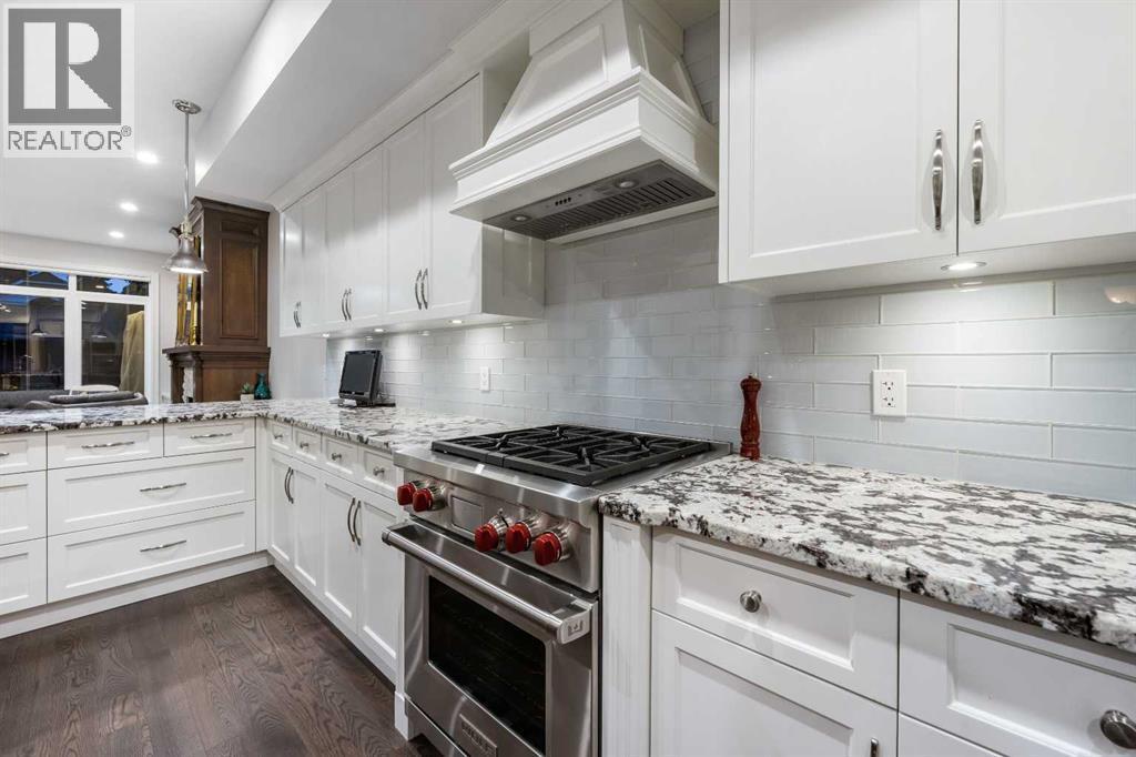 The chef-inspired kitchen features a Wolf gas range, Miele dishwasher, granite countertops, full-height custom cabinetry and a statement island, perfect for meal prep and entertaining - 922 5 Street Nw, Calgary, AB - Indoor Photo Showing Kitchen With Upgraded Kitchen