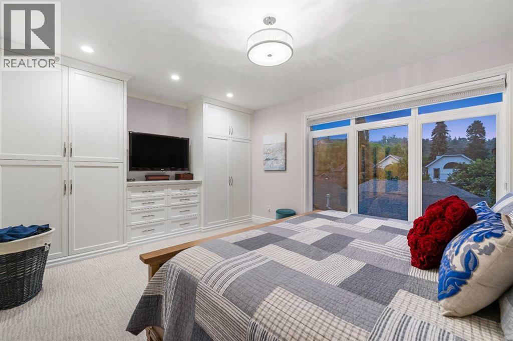 Spacious primary suite with oversized Lux windows, custom built-ins, a spa-like ensuite with inlaid heated tile flooring, dual sinks, and premium fixtures - 922 5 Street Nw, Calgary, AB - Indoor Photo Showing Bedroom