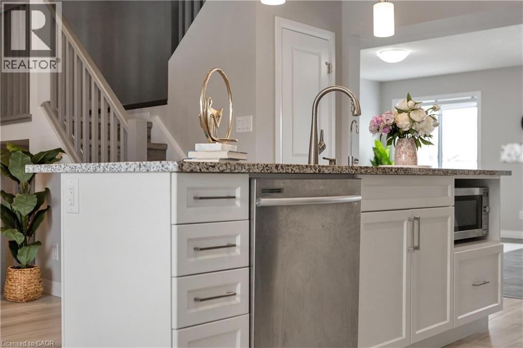 Kitchen with white cabinets, light stone counters, appliances with stainless steel finishes, light wood-style floors, and pendant lighting - 492 Wismer Street, Waterloo, ON - Indoor Photo Showing Kitchen With Upgraded Kitchen