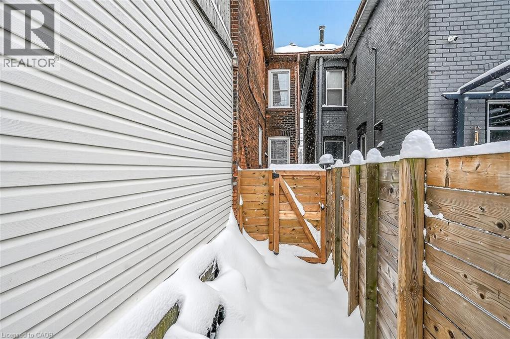 View of property exterior with brick siding and a gate - 77 Barton Street E Unit# 1, Hamilton, ON - Outdoor