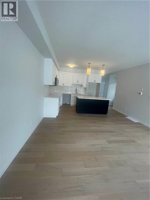 Kitchen with decorative backsplash, light countertops, open floor plan, a center island, and light wood-style floors - 152 Queensbrook Crescent, Cambridge, ON - Indoor Photo Showing Other Room