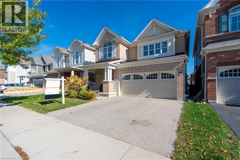 View of front of home featuring a garage, driveway, brick siding, covered porch, and a residential view - 335 Falling Green Crescent, Kitchener, ON - Outdoor With Facade