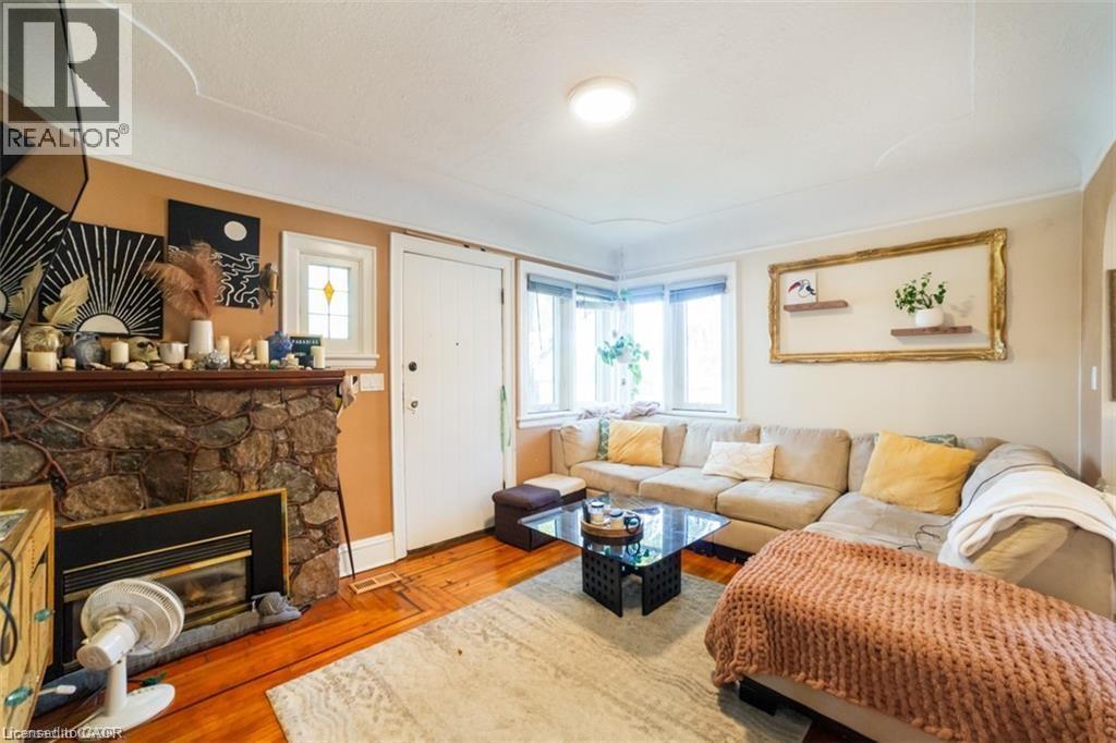 Living area with wood finished floors and a stone fireplace - 41 Paradise Road S, Hamilton, ON - Indoor Photo Showing Living Room With Fireplace