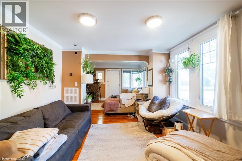 Living area featuring wood finished floors, a fireplace with raised hearth, and ornamental molding - 41 Paradise Road S, Hamilton, ON - Indoor Photo Showing Living Room