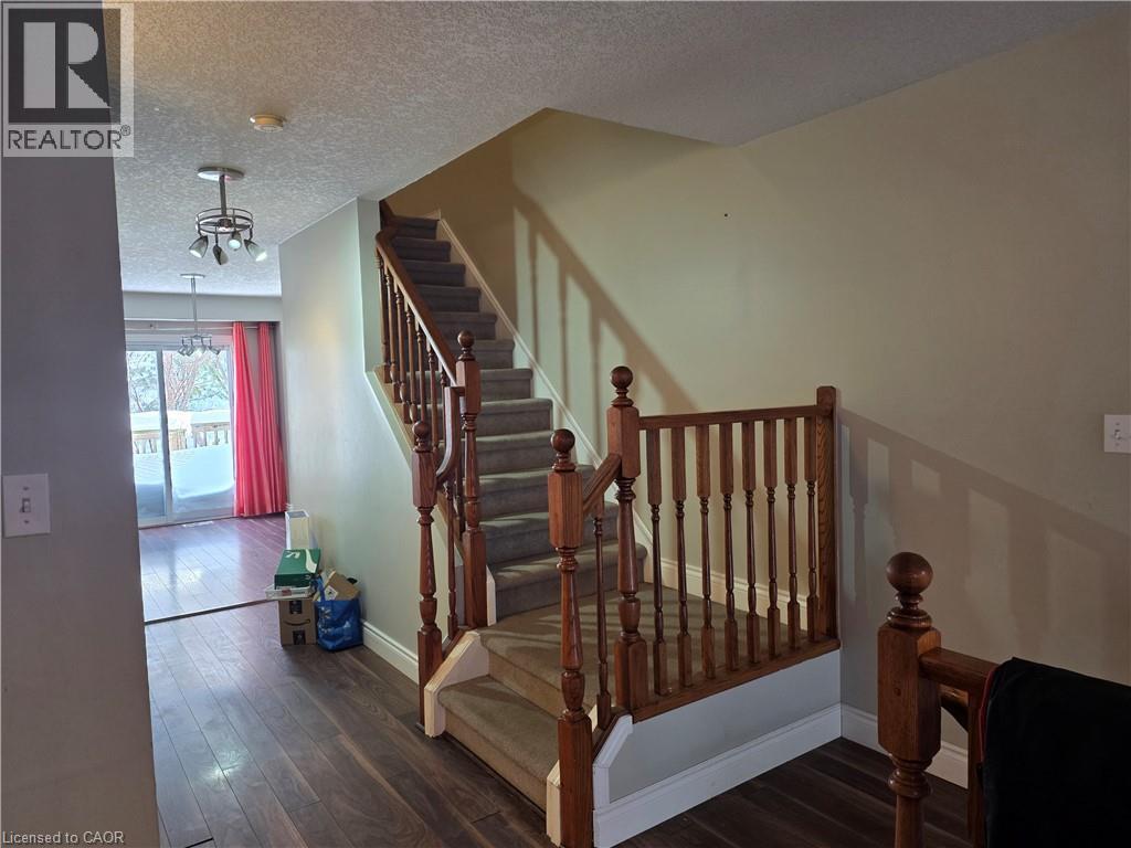 Staircase with hardwood / wood-style floors, a textured ceiling, and hanging lights - 220 Snowdrop Crescent, Kitchener, ON - Indoor Photo Showing Other Room