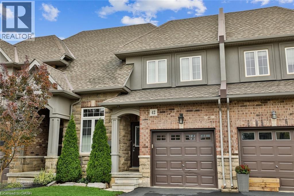 View of front facade featuring a shingled roof, an attached garage, driveway, and stone siding - 42 Madonna Drive, Hamilton, ON - Outdoor With Facade
