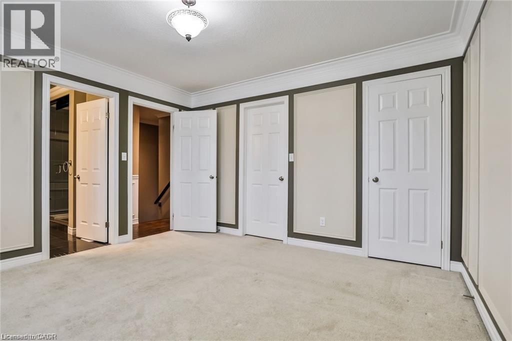 Unfurnished bedroom with carpet flooring, ornamental molding, and two closets - 42 Madonna Drive, Hamilton, ON - Indoor Photo Showing Other Room