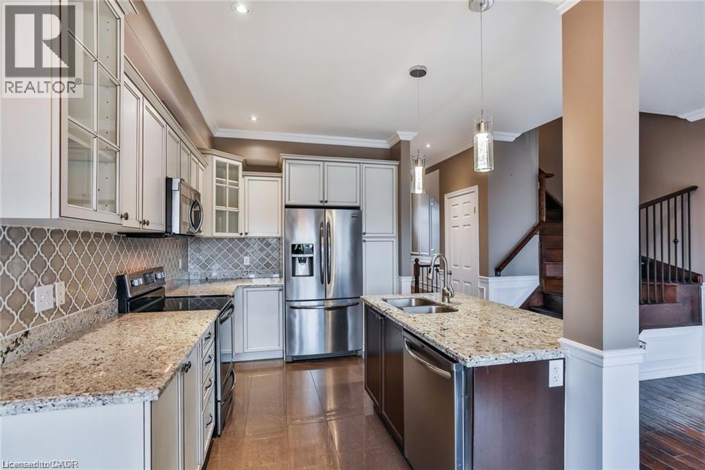 Kitchen with stainless steel appliances, glass insert cabinets, hanging light fixtures, light stone counters, and backsplash - 42 Madonna Drive, Hamilton, ON - Indoor Photo Showing Kitchen With Stainless Steel Kitchen With Double Sink With Upgraded Kitchen
