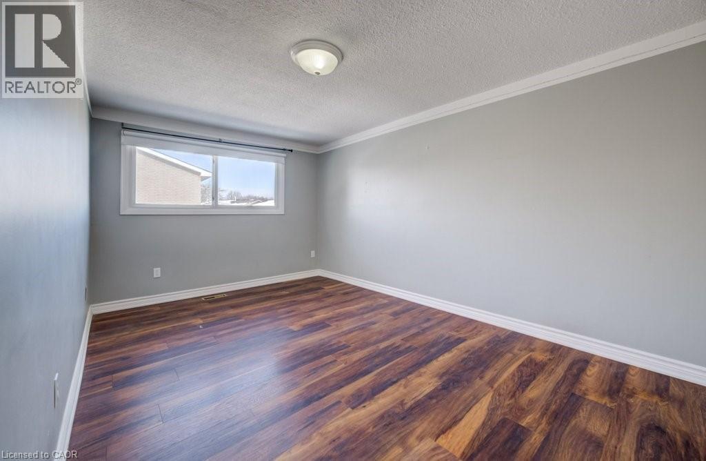 Unfurnished room with dark wood-type flooring, ornamental molding, and a textured ceiling - 54 Nicklaus Drive, Hamilton, ON - Indoor Photo Showing Other Room