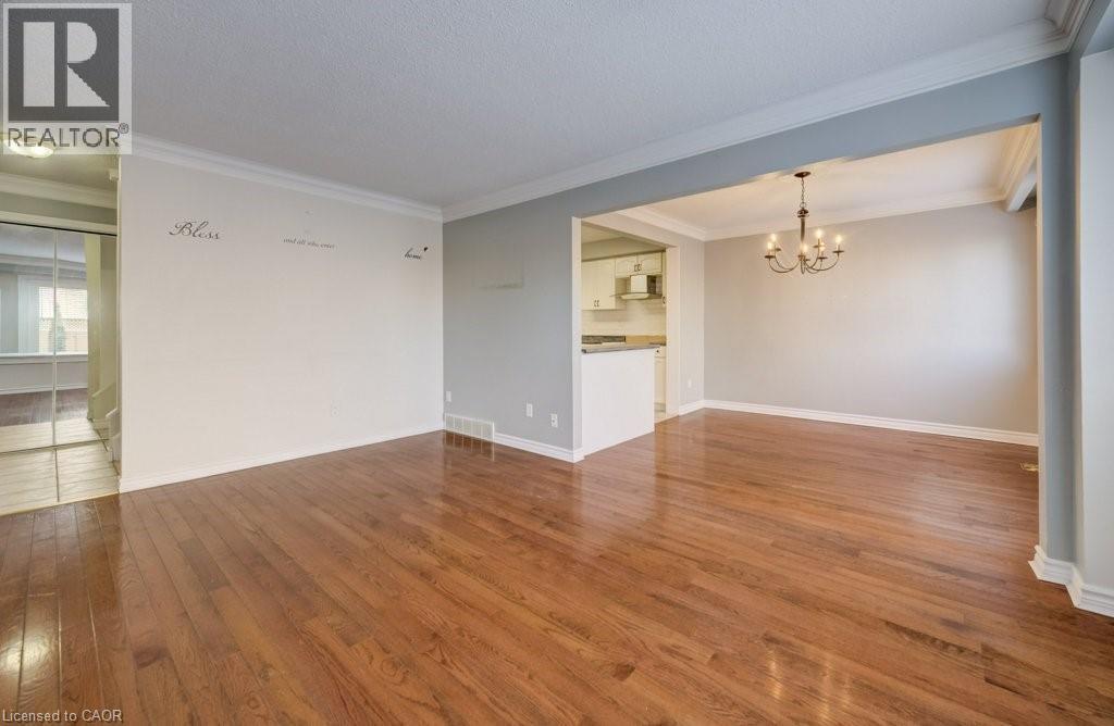Empty room with a chandelier, wood finished floors, and crown molding - 54 Nicklaus Drive, Hamilton, ON - Indoor Photo Showing Other Room