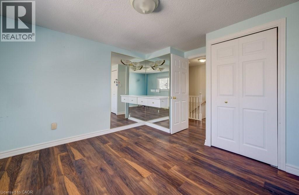 Unfurnished bedroom with a textured ceiling, dark wood-style floors, and a closet - 54 Nicklaus Drive, Hamilton, ON - Indoor Photo Showing Other Room