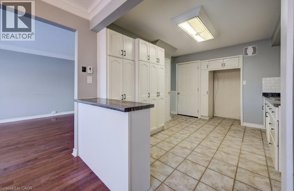 Kitchen featuring dark countertops, white cabinets, crown molding, a textured ceiling, and light wood-style flooring - 54 Nicklaus Drive, Hamilton, ON - Indoor Photo Showing Other Room