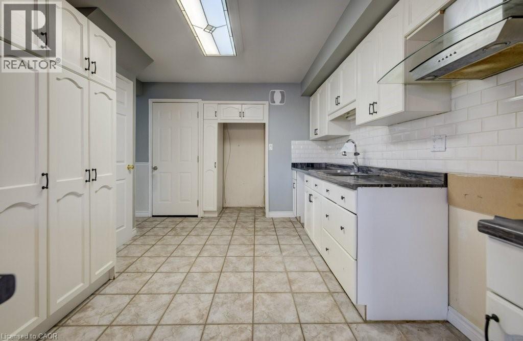 Kitchen with under cabinet range hood, white cabinetry, and tasteful backsplash - 54 Nicklaus Drive, Hamilton, ON - Indoor Photo Showing Kitchen