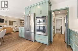 Kitchen featuring green cabinets, stainless steel appliances, open floor plan, recessed lighting, and light wood-style flooring -