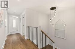 Hallway with an upstairs landing, wood finished floors, and recessed lighting -