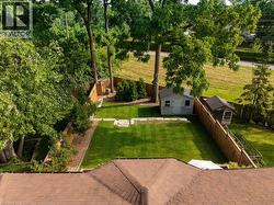 Fenced backyard with an outbuilding, a patio area, and view of scattered trees -