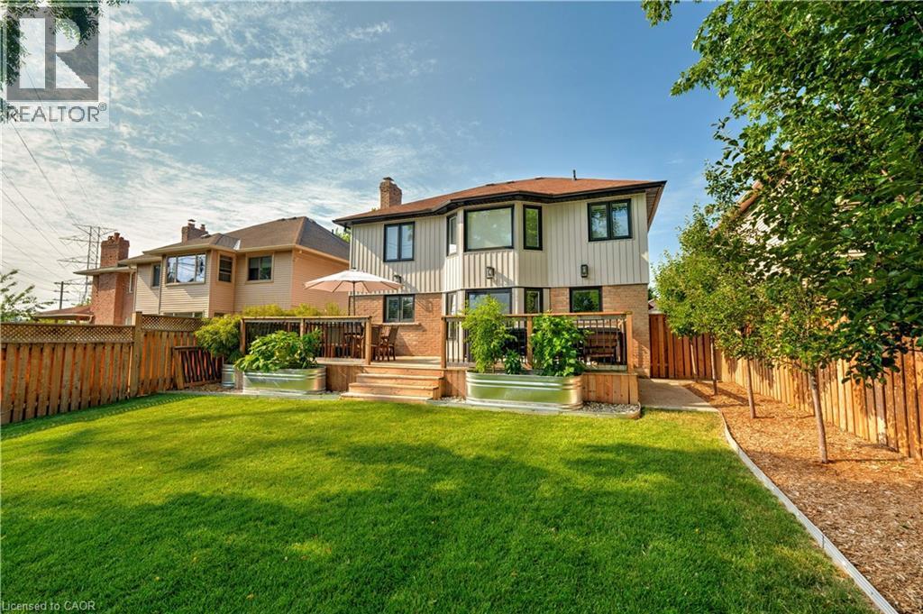 Back of house with brick siding, a wooden deck, a fenced backyard, and a chimney - 697 Lambshead Drive, Burlington, ON - Outdoor